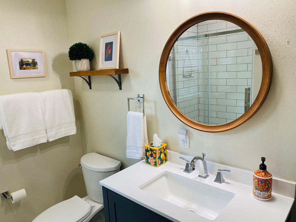 Bathroom with round mirror and dark vanity