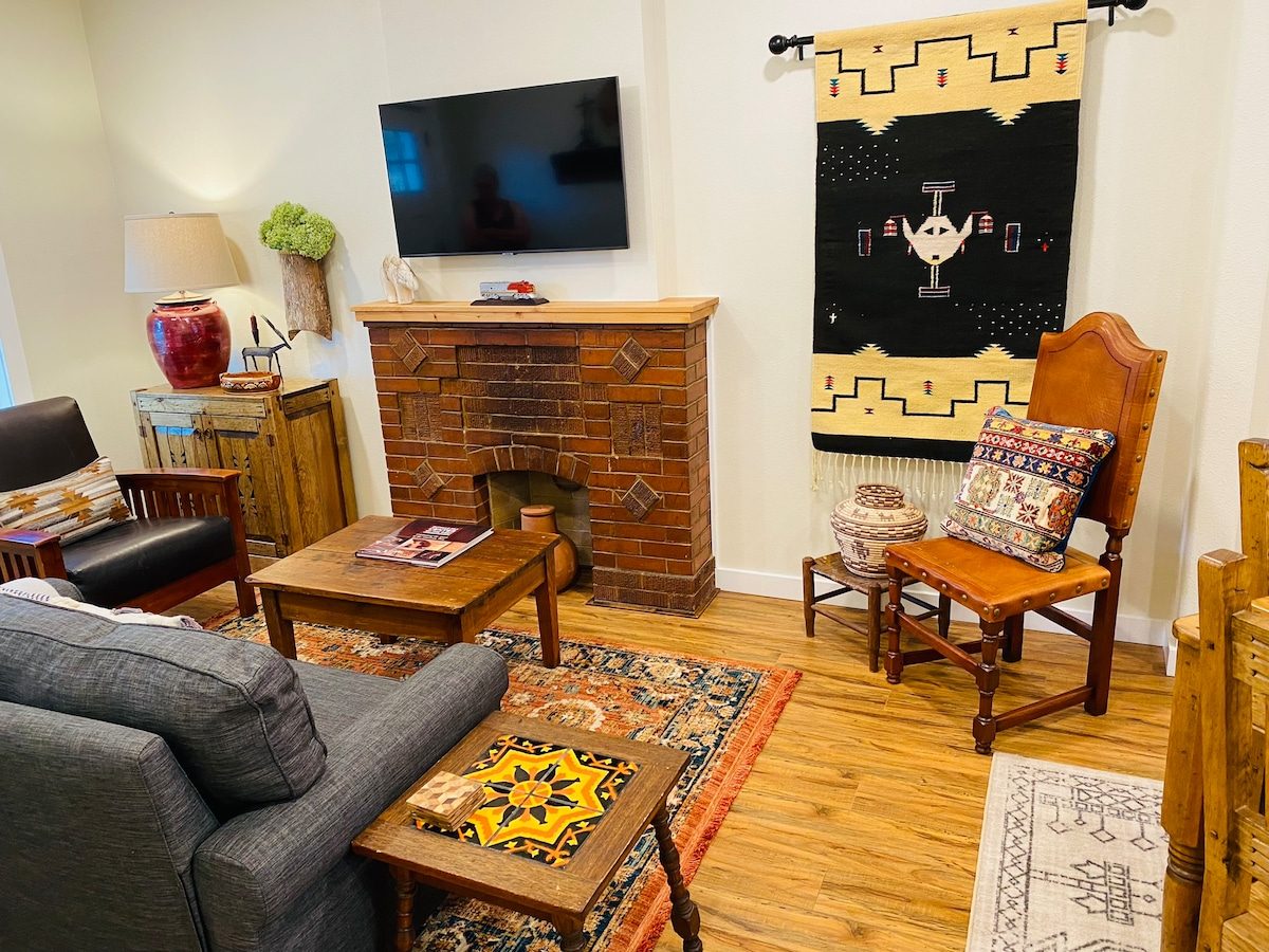 Living room with brick fireplace, armchair and Southwestern rug