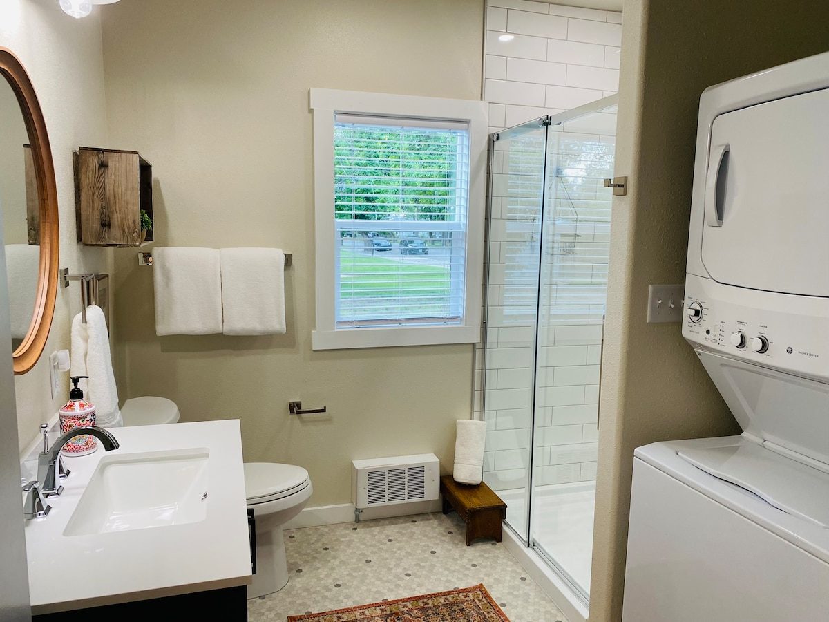 Bathroom with glass shower and stacked washer and dryer