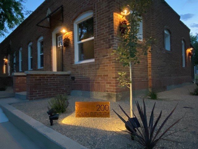 Brick casita wall with sconce lighting and a desert garden