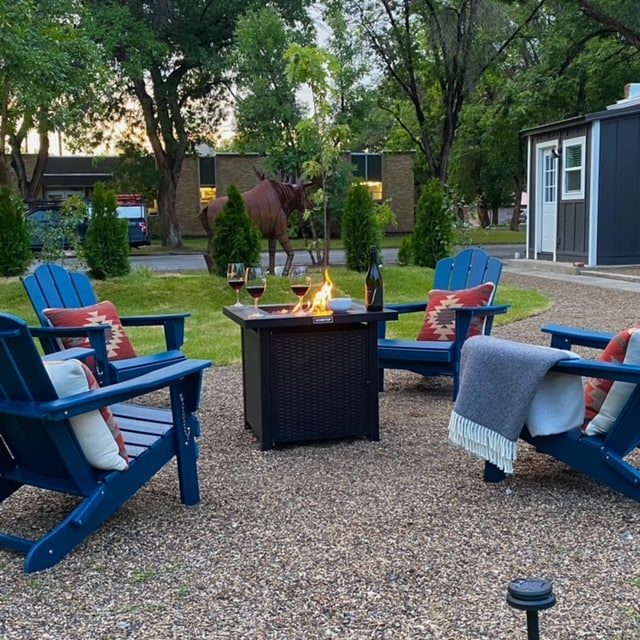 Fire pit with blue Adirondack chairs on a gravel patio