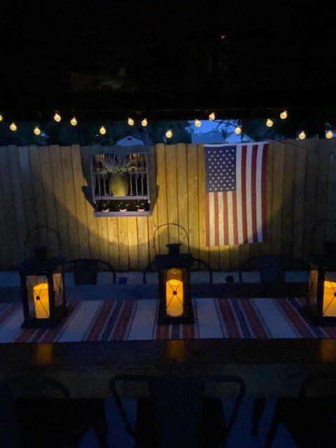Patio dining table lit by lanterns and string lights at night