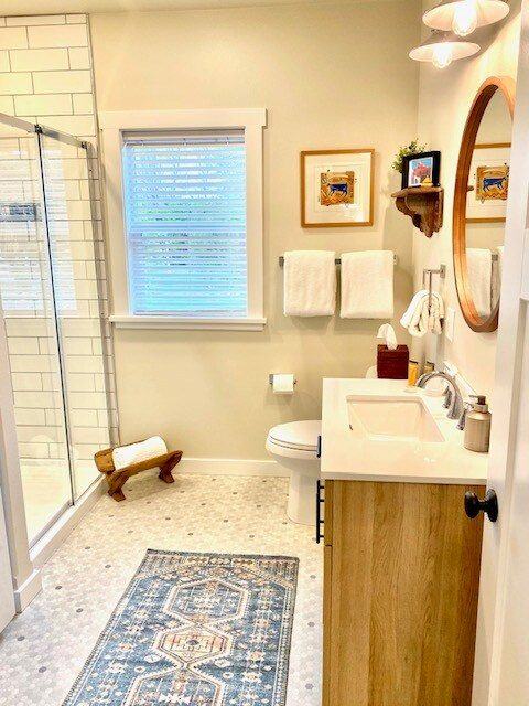 Bathroom with glass shower and a blue patterned rug